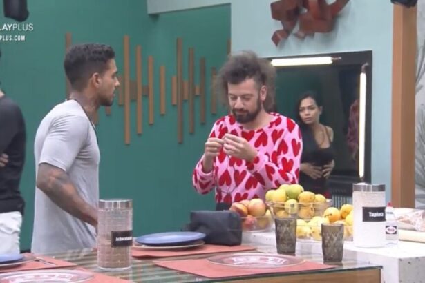 Matheus em pé de camisa cinza de frente para Cartolouco que está de roupa de coração.