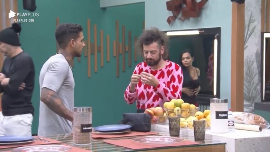 Matheus em pé de camisa cinza de frente para Cartolouco que está de roupa de coração.