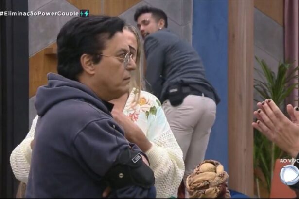 Nahim com semblante sério olhando para frente e Matheus atrás da imagem com as mão no joelho rebolando o bumbum.