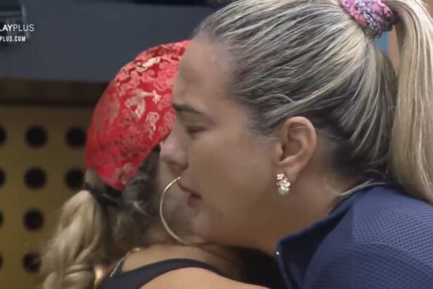 Andreia com os olhos fechado, chorando abraçada com Adryana.