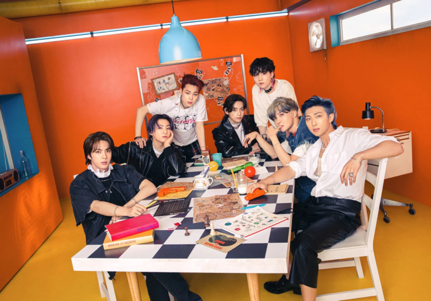 Grupo BTS reunido em volta de uma mesa