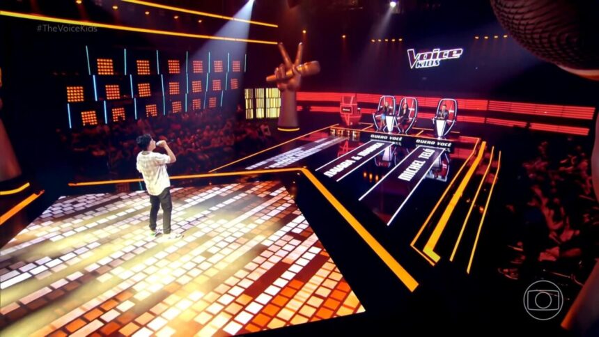 Mateus Cassemiro cantando no centro do palco do The Voice Kids