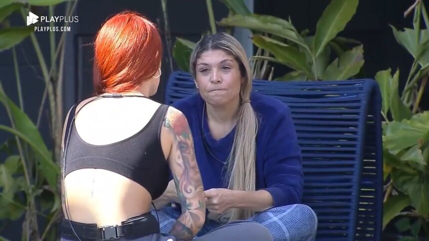 Brenda de costas para Adryana na área externa do Power Couple.