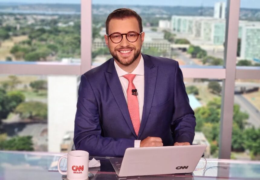 Cassius Zeilmann em foto posada nos estúdios da CNN Brasil em Brasília, com uma visão da cidade ao fundo