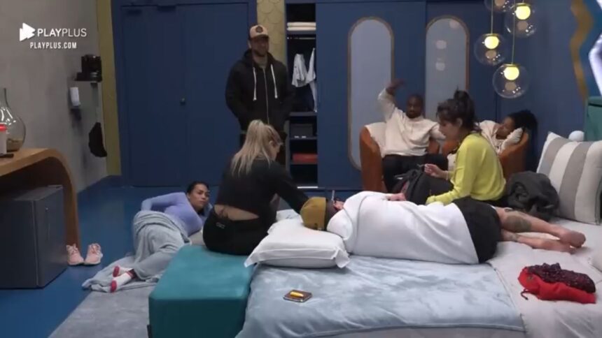 Eliza deitada no chão de um dos quartos do Power Couple. Hadballa em pé com os braços para trás, ao lado de Bruno sentado em uma cadeira, próximo de Michele. Na cama, Karol de costa para imagem perto de Anne e Pe Lanza.