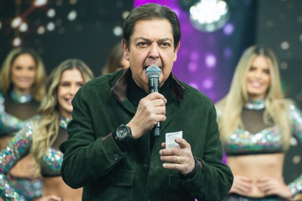 Fausto Silva com microfone e tabela na mão durante gravação do seu programa