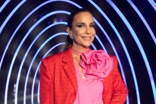 Ivete Sangalo com uma blusa rosa e um flor em cima do busto, nos estúdios do The Masked Singer Brasil