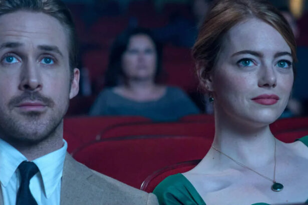 Ryan Gosling de palitó e gravata e Emma Stone de vestido verde e batom vermelho olhando para a tela do cinema durante gravação do filme La La Lan - Cantando Estações