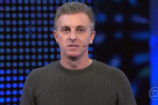 Luciano Huck vestindo um cardigã verde escuro, discursando nos estúdios do Domingão