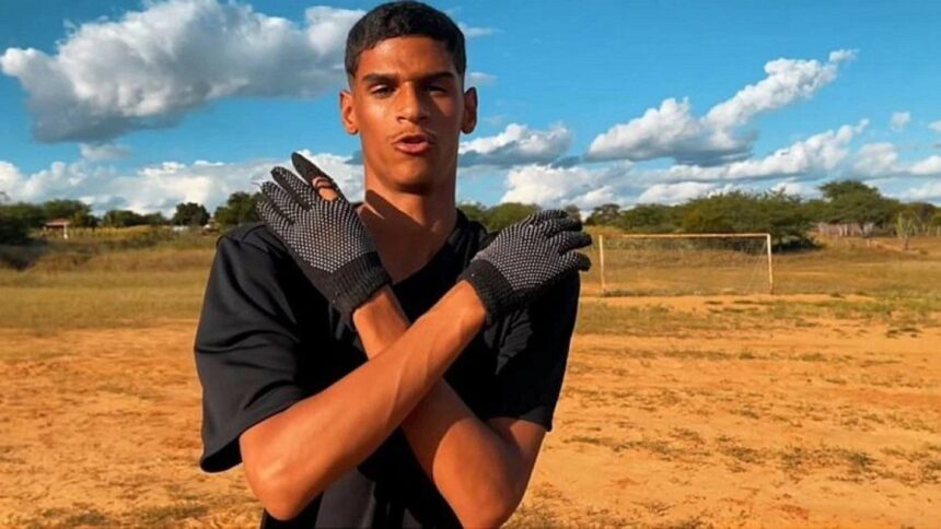 Iran Ferreira, o Luva de Pedreiro, com os braços abraçados no corpo, na pose do "Receba!" em um campo de terrão