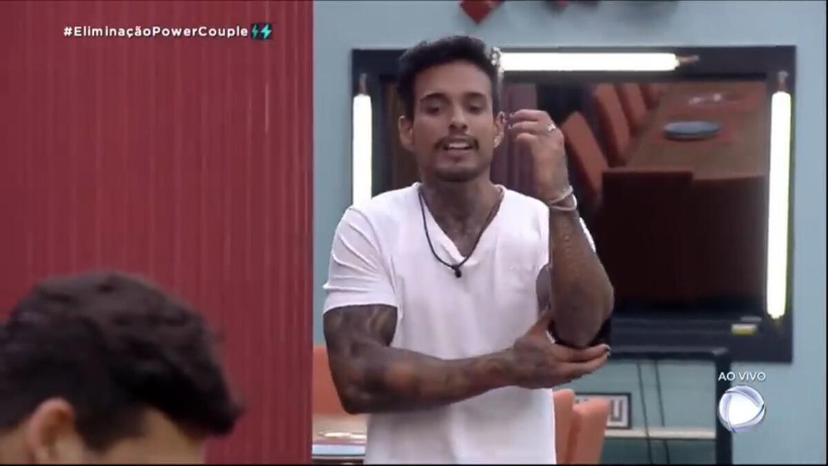 Matheus de roupa branca na sala do Power Couple Brasil.