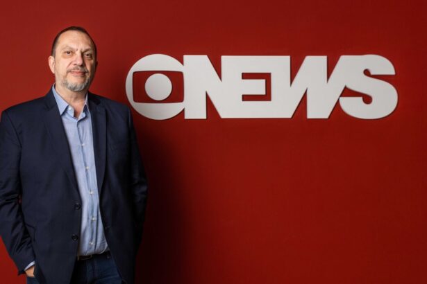 Mauro Paulino em frente a uma parede vermelha, com o logo da GloboNews estampado em branco