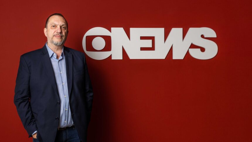 Mauro Paulino em frente a uma parede vermelha, com o logo da GloboNews estampado em branco