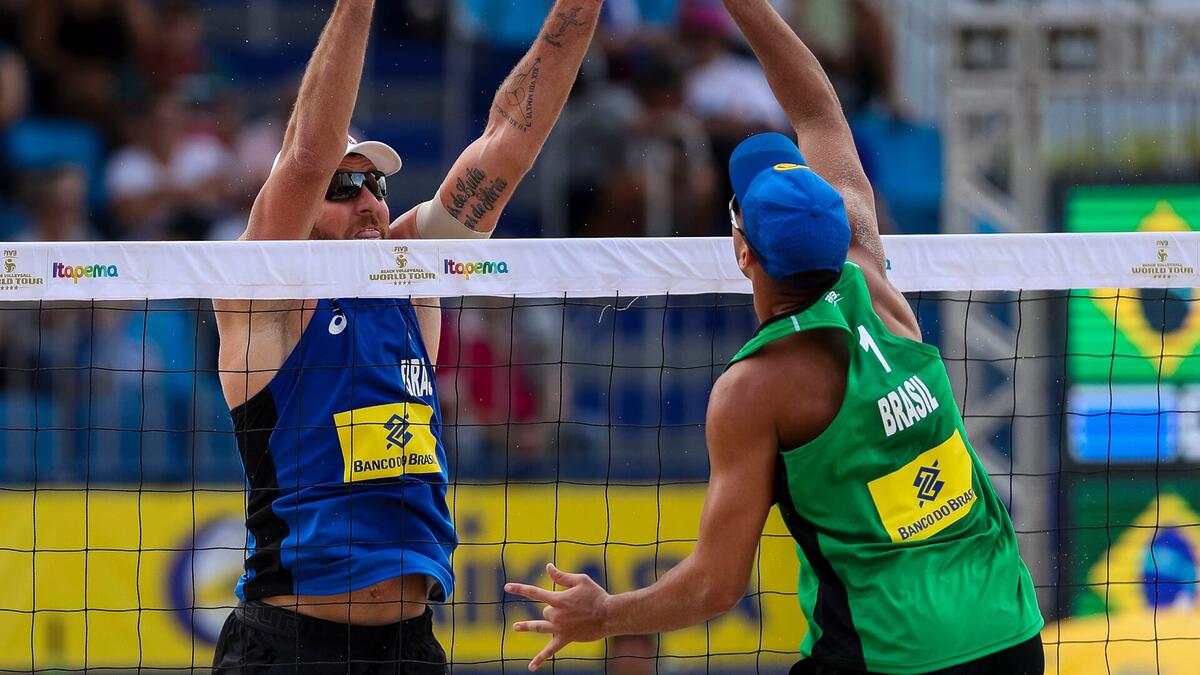 Jogadores de Vôlei de Praia disputando a bola na rede