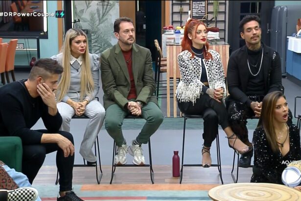 Nandinho, Adryana, Albert, Brenda, Matheus e Ivy assistem ao vídeo na TV da sala do Power couple que mostra cochicho de Anne e Karol