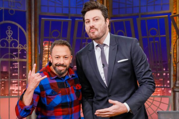 Fabio Gueré sorrindo, de camisa quadriculada azul e vermelha, fazendo símbolo do rock in roll com a mão direita ao lado de Danilo Gentili, que está de palitó e gravata, apontando para o humorista