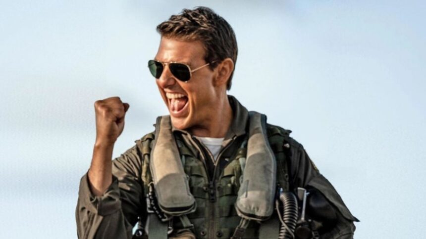 Tom Cruise com óculos de sol, fardamento, vibrando durante gravação do filme Top Gun, da Paramount