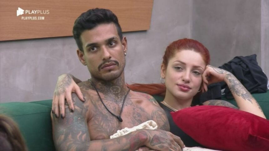 Matheus sem camisa ao lado de Brenda no sofá do Power Couple.