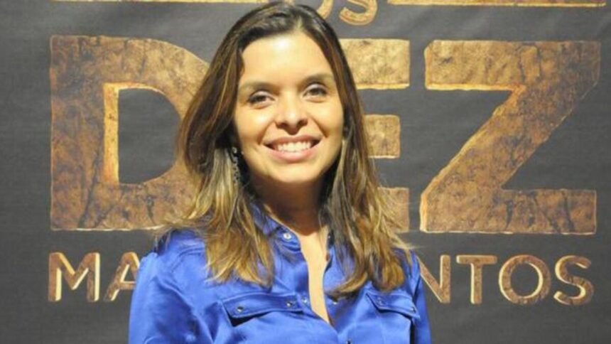 Vivian de Oliveira em frente ao banner com o logo da novela Os Dez Mandamentos