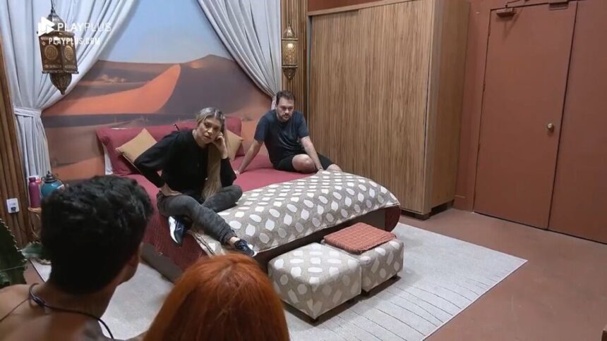 Albert e Adryana sentados na cama no Power Couple. De costa na imagem aparece Brenda e Matheus.