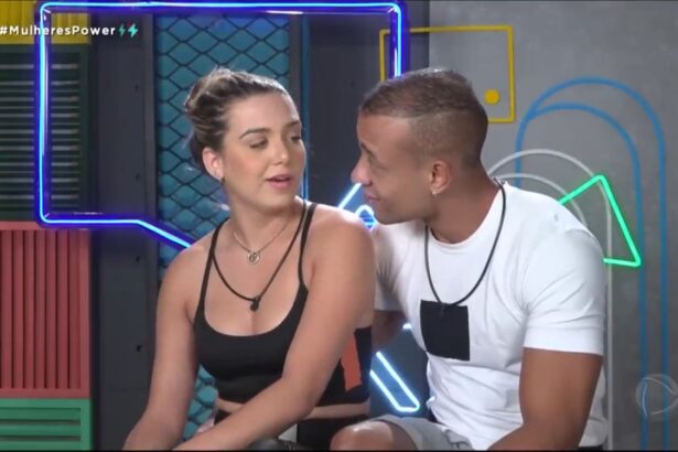 Karol de roupa preta e cabelo amarrado ao lado de Mussunzinho na cabine de depoimentos do Power Couple.