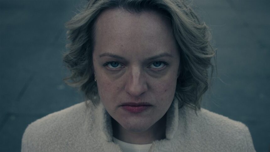 June Osborne, personagem de Elisabeth Moss, olhando para câmera concentrada durante gravação de The Handmaid's Tale