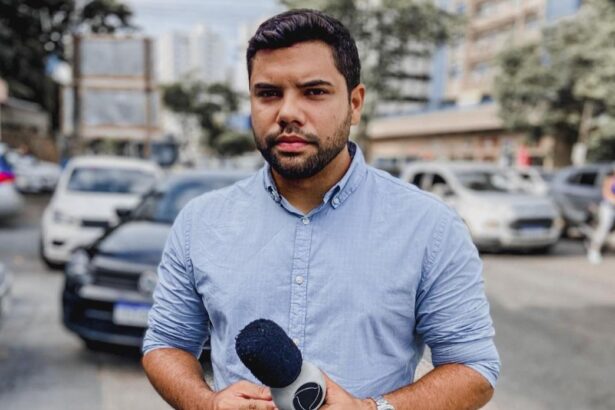 Alex Silvestre segurando um microfone da Record TV, nos bastidores de uma reportagem