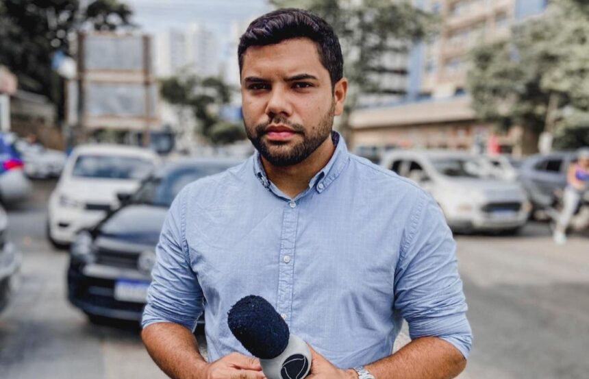 Alex Silvestre segurando um microfone da Record TV, nos bastidores de uma reportagem