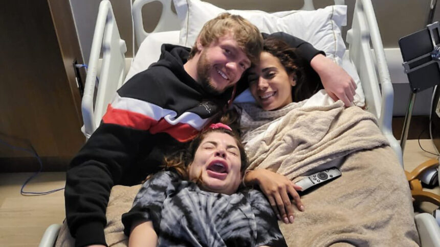 Anitta, Gkay e Murda Beatz, deitados e abraçados em uma cama de hospital