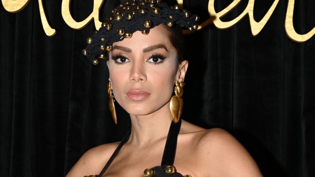 Anitta com um chapéu preto, em foto posada nos bastidores de um evento