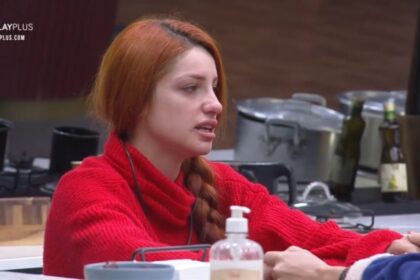 Brenda vestida de roupa vermelha sentada na mesa da cozinha do Power Couple.