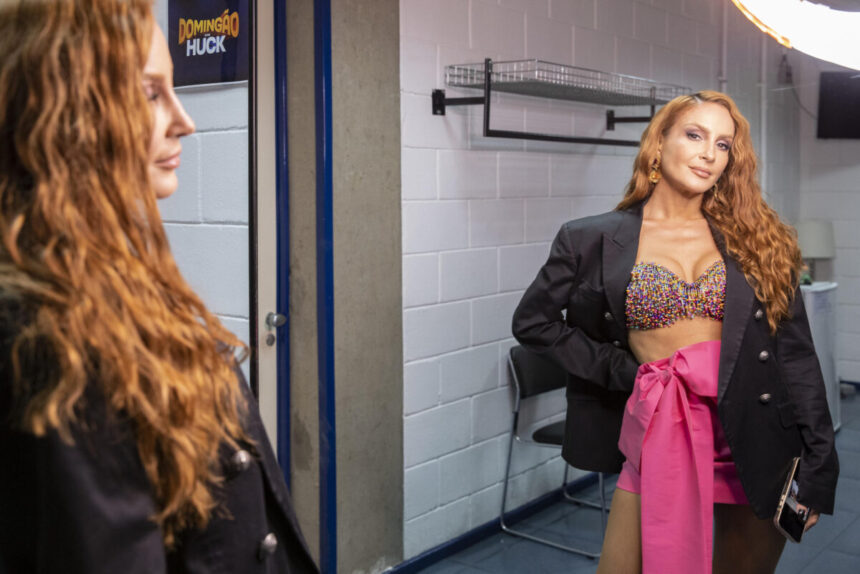 Claudia Leitte, nos bastidores do Domingão, em frente a um espelho e observando o seu reflexo contido nele