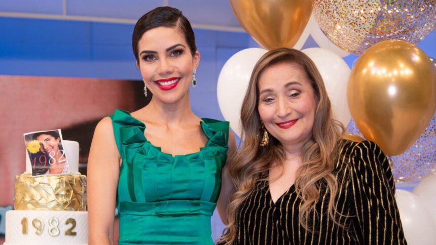 Dani Albuquerque de vestido verde, sorrindo, abraçando Sonia Abrão em frente ao cenário do seu aniversário no programa Sensacional, da RedeTV!