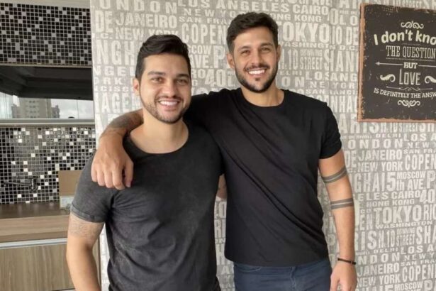 Diogo e Rodrigo Mussi abraçados, em frente uma parede de apartamento