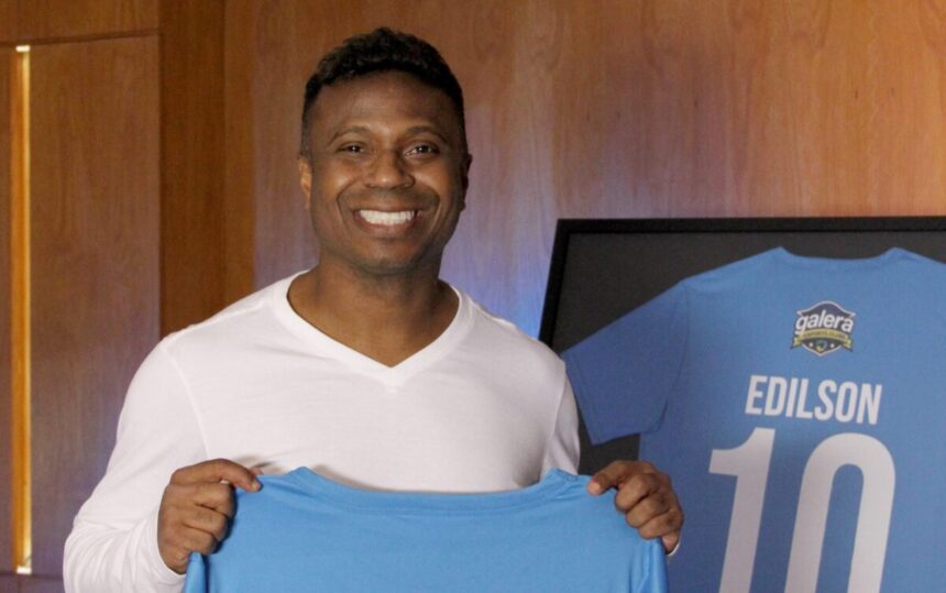 Edilson Capetinha segurando uma blusa azul, com o logo Galera Esporte Clube