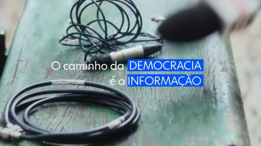 Trecho da campanha Onde nascem as notícias, da Globo. Imagem tem a frase "o Caminho da democracia é a informação", em meio a microfones de imprensa