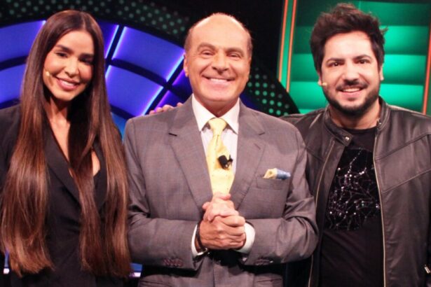 Kerline de vestido preto, cabelo solto, sorrindo; Marcelo de Carvalho sorrindo, de mãos dadas, de palitó cinza e gravata verde clara; Thiago de jaqueta de couro, camisa e calça jeans preta, sorrindo durante gravação do programa O Céu é o Limite, da RedeTV!