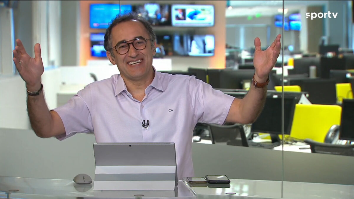 Marcelo Barreto com os braços abertos, nos estúdios do Redação SporTV, mostrando a redação de esportes da Globo ao fundo
