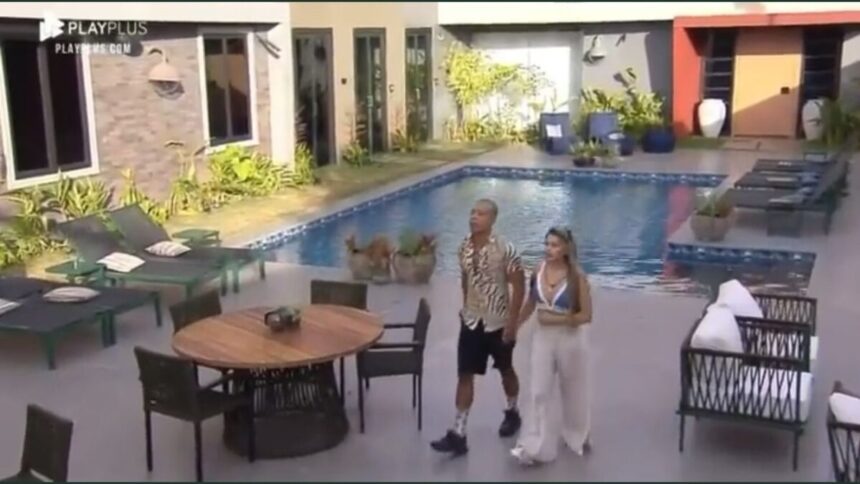 Karol e Mussunzinho na área externa do Power Couple, próximos da piscina.