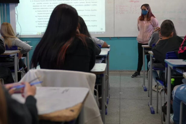 Alunos em uma sala de aula, sentados nas carteiras, com uma professora em pé na frente do quadro. Trecho do Profissão Repórter sobre saúde mental nas escolas