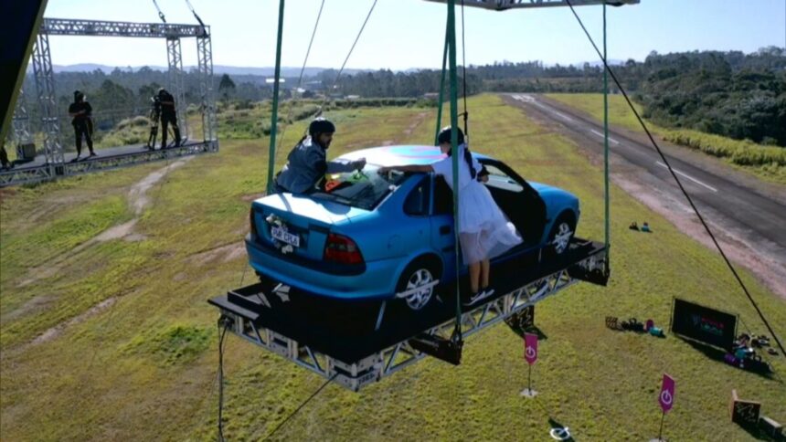 Na imagem aparece um carro pendurado por guindaste para a Prova dos Casais.