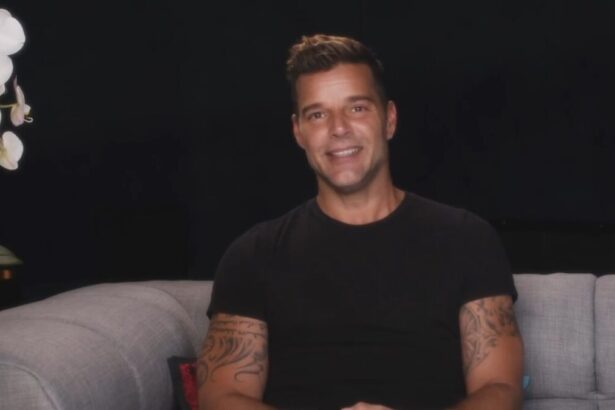 Ricky Martin sentado em um sofá vestindo preto