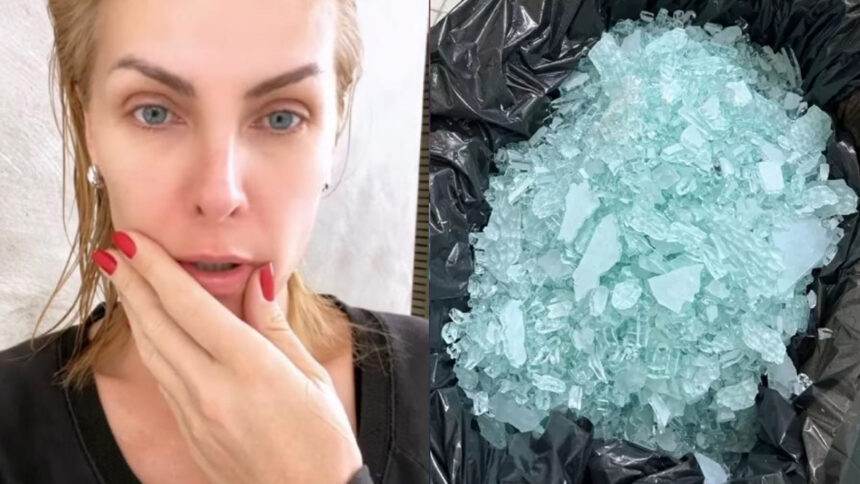 Ana Hickmann com sembrante assustado, unha vermelha, camisa preta, cabelo molhado, com a mão na boca durante gravação de storys para instagram; saco plástico preto com pedaços de vidro