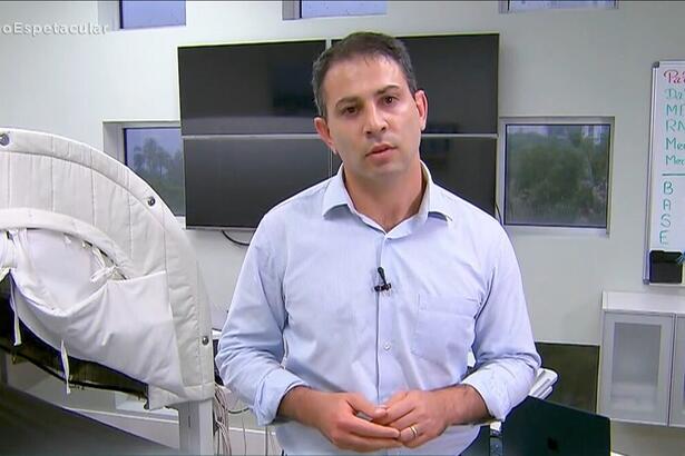 André Tal com camisa social azul clara dentro de um consultório nos Estados Unidos gravando matéria para o Domingo Espetacular, da Record TV