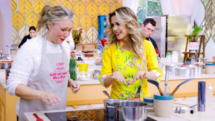 Beca Milado ao lado de uma participante, em frente ao fogão, em trecho de uma prova na estreia do Bake Off Brasil 8