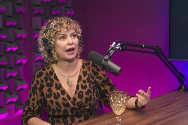 Bárbara Borges de vestido animal print de onça, decotada, colar de prata sentada numa cadeira de ferro preta, com a mão na bancada do podcast Papagaio Falante