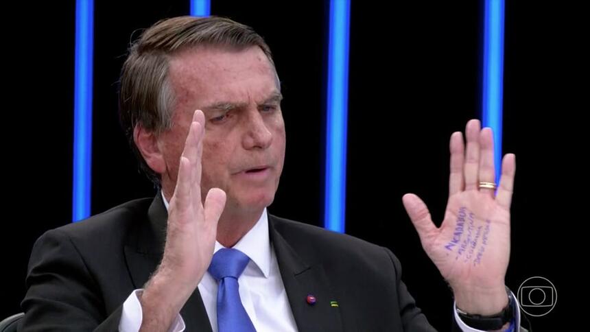 Bolsonaro em trecho da sabatina no Jornal Nacional, com os braços apertos em frente ao rosto