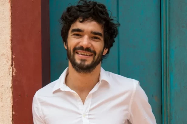 Caio blat, de camisa social branca, sorrindo, durante ensaio fotográfico