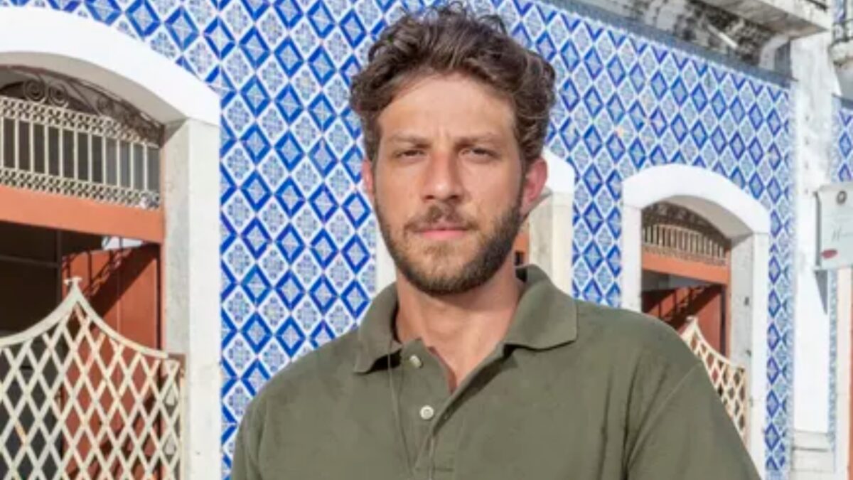 Chay Suede com blusa verde em cena de Travessia