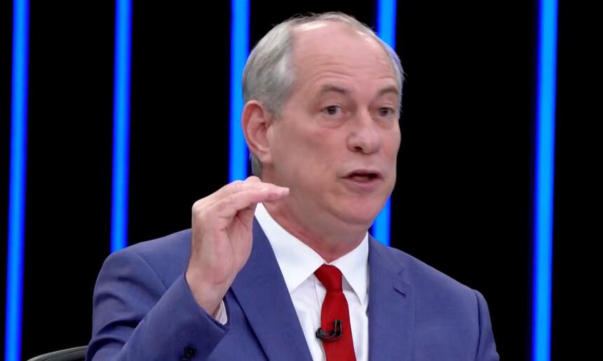 Ciro Gomes de blazer azul, camisa branca e gravata vermelha com semblante sério, sentado durante entrevista no jornal nacional, da TV Globo